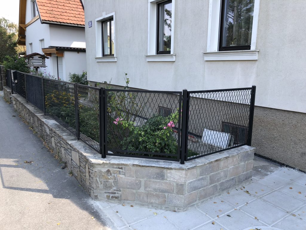 Zaun aus Streckmetall auf einer Natursteinmauer
