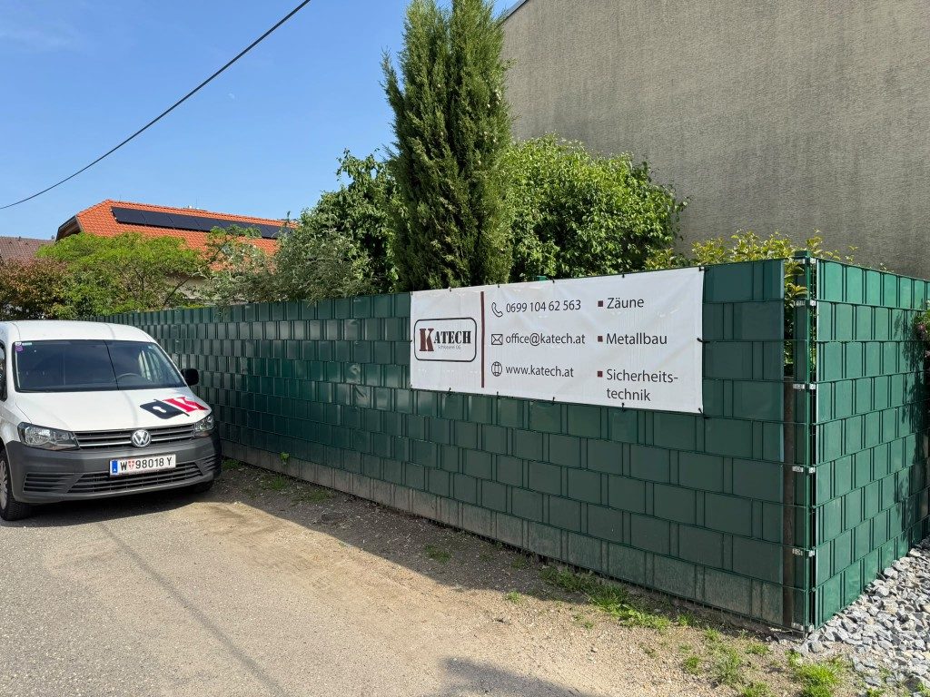 Grüner Sichtschutzzaun mit Katech-Banner und Servicefahrzeug